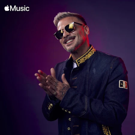 Man with sunglasses wearing an embroidered denim jacket clapping hands against a purple gradient background