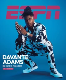 Athletic black man crouching in patterned matching shirt and trousers against a vibrant blue studio backdrop.