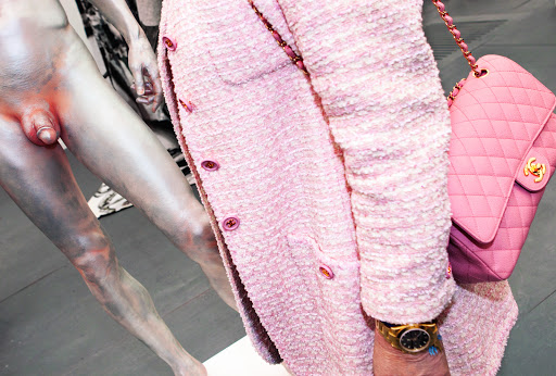 Nude sculpture with pink tweed jacket and purse, contrasted textures and colors, artful display of form and fashion, studio aesthetic.