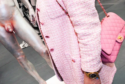 Nude sculpture with pink tweed jacket and purse, contrasted textures and colors, artful display of form and fashion, studio aesthetic.