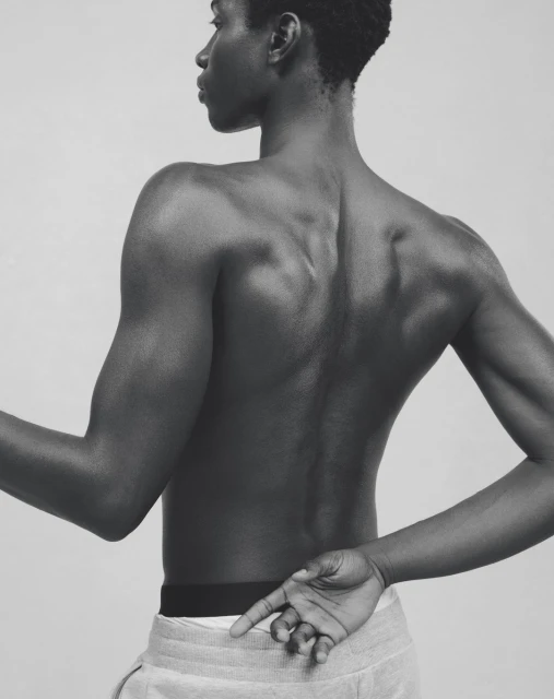 Striking monochrome portrait of a bare-chested Black male model with arms crossed, showcasing muscular physique and minimalist style.