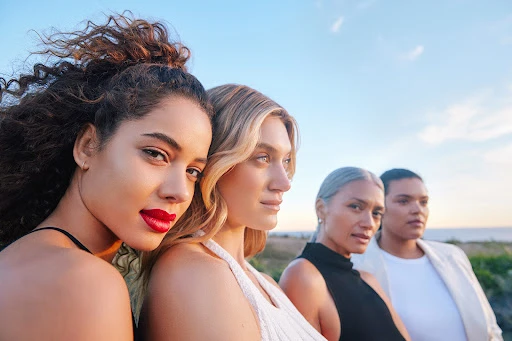 Low angle portrait of four diverse women standing against a clear blue sky, captured by Kayla Varley.