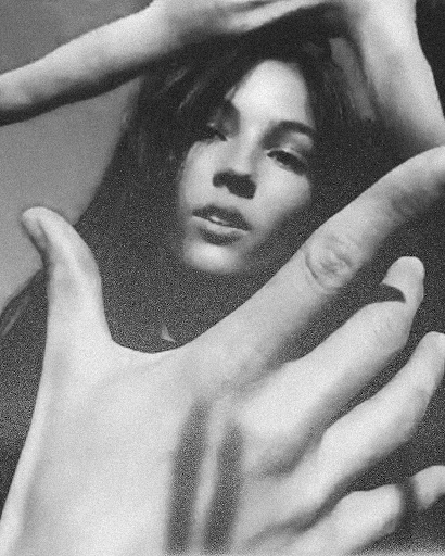Monochrome portrait of a woman framed by hands in the foreground, with heavy film grain and soft focus.