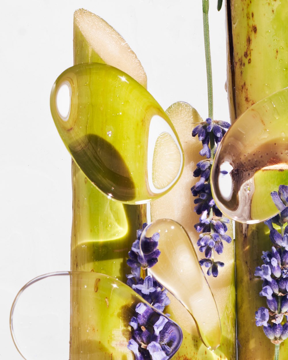 Botanical beauty shot featuring bamboo stalks, lavender blossoms, and transparent gel droplets against a pristine white backdrop.