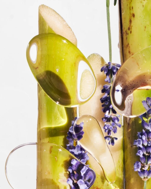 Botanical beauty shot featuring bamboo stalks, lavender blossoms, and transparent gel droplets against a pristine white backdrop.