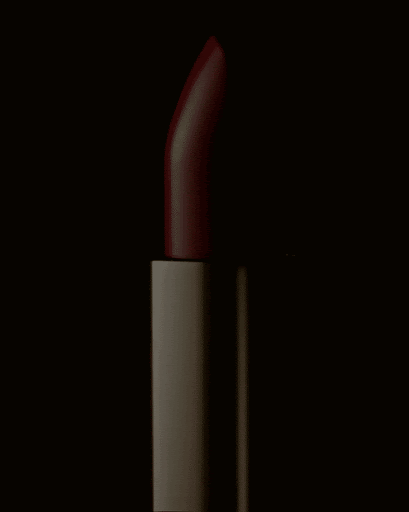 Close-up studio shot of a single red lipstick tube against a black background, highlighting its shape, color, and texture.