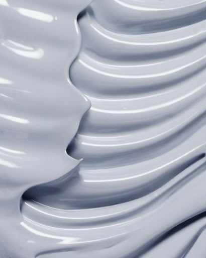 Abstract close-up of a thick grey cream with shiny texture, showing a wavy pattern and smooth surface, perfect for beauty product.
