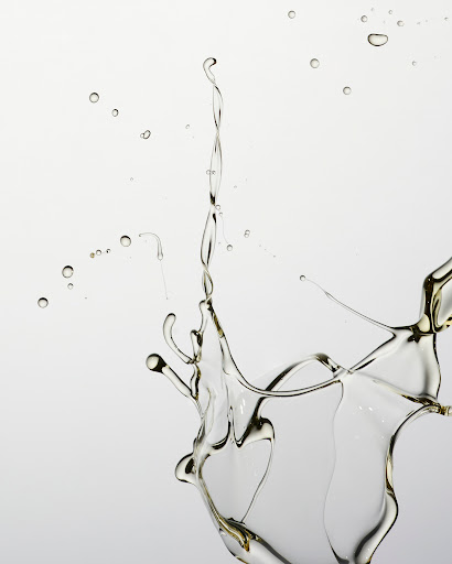 Close-up studio shot of clear liquid splashing against a white background, creating dynamic shapes and patterns in mid-air.