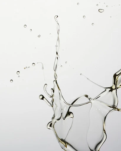 Close-up studio shot of clear liquid splashing against a white background, creating dynamic shapes and patterns in mid-air.