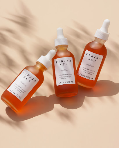Three bottles of Tyrion Sea antioxidant facial oil by Skinvolve are arranged against a light beige background with shadow from foliage.