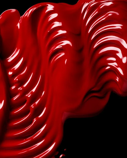 Close-up of glossy red paint swirled against a black background, highlighting textures and patterns in a visually striking, abstract design.