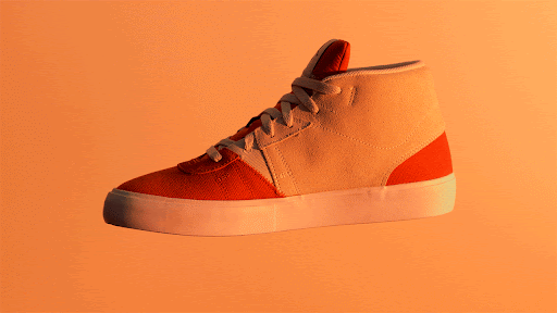 Studio shot of a high-top sneaker with a white sole and orange and white upper against an orange background, showcasing footwear design.