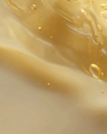 Close-up of viscous honey-colored liquid with surface tension, small bubbles, and soft texture; ideal for beauty product marketing.