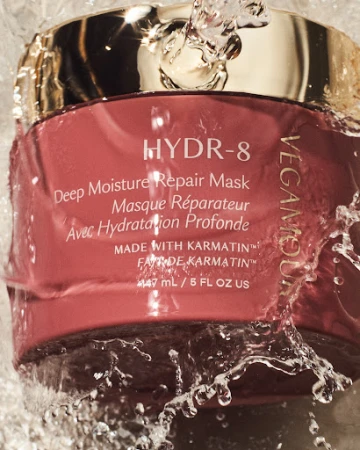 Vegamour HYDR-8 Deep Moisture Repair Mask jar with water splashing on it, gold lid and pink container, skincare product shot.