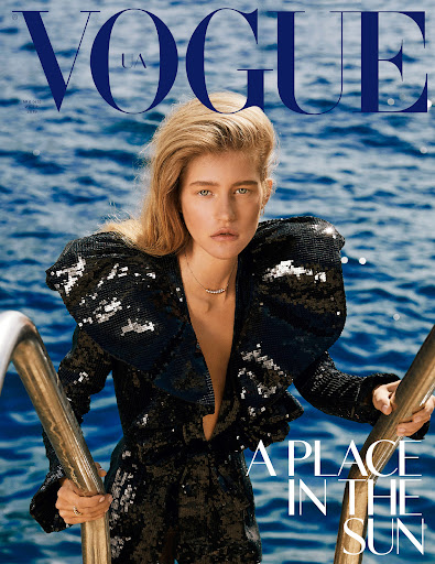 Vogue UA cover featuring a blonde woman in a black sequined jumpsuit, holding onto a metal railing with a blurry ocean backdrop.