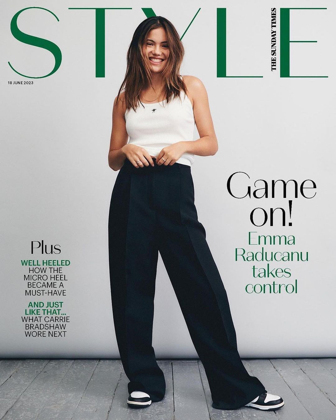 Emma Raducanu poses on the cover of Style magazine, wearing a white top and black pants, smiling against a white backdrop.