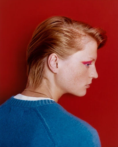 An adult man in a black suit poses in a photo studio with soft lighting, showcasing fashion and portrait photography.