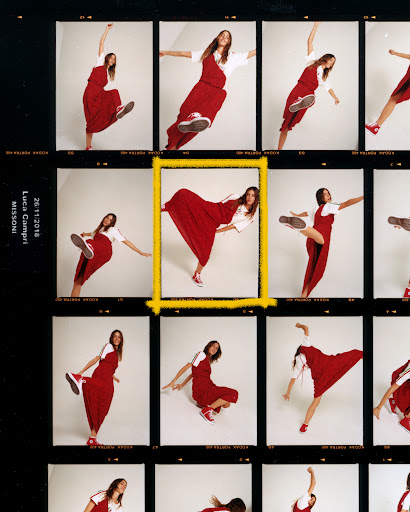 Fashion shot of a young adult woman in a red dress and white shirt striking a dynamic pose, captured in a film strip style image.