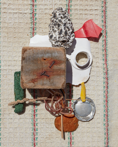 Abstract still life arrangement of textured and colorful objects on a striped textile background, creating a visually intriguing composition.