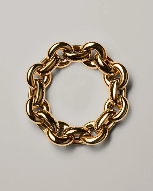 Close-up studio shot of a circular golden chain necklace on a gray surface, jewellery, gold metal with reflective light, fashion concept.