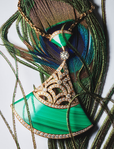 Elegant gold necklace with malachite and diamond pendant on a peacock feather background, studio lighting, jewelry still life.