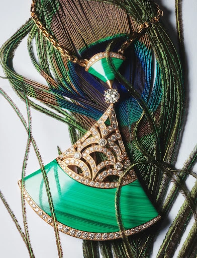 Elegant gold necklace with malachite and diamond pendant on a peacock feather background, studio lighting, jewelry still life.