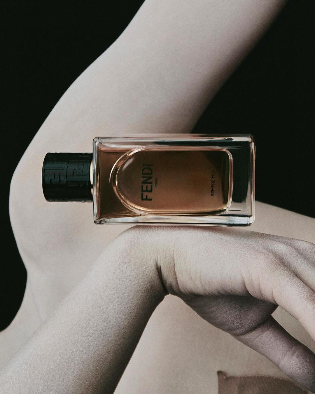 Fendi perfume bottle displayed on fair skin against a black background, product shot for fragrance marketing.