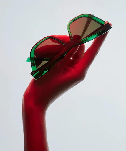 Adult female model in fashion photo shoot, wearing a dark blazer and sunglasses, in a photo studio with strobe lighting.