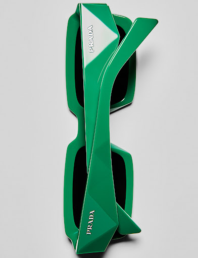 Top-down studio shot of green Prada sunglasses with white logo detailing, showcasing modern design and contrasting colors against a neutral background.