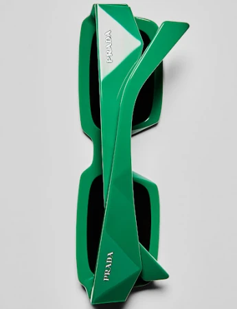 Top-down studio shot of green Prada sunglasses with white logo detailing, showcasing modern design and contrasting colors against a neutral background.