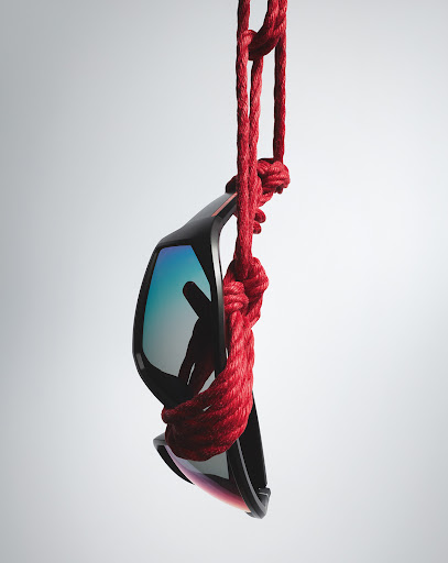 Sunglasses are suspended by a red rope against a gradient background, showcasing eyewear and creative suspension in a clean, studio setting.