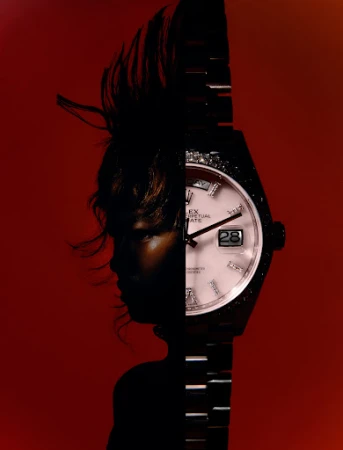 Dramatic composite of a wristwatch and a silhouetted person against a red backdrop, blending horology with abstract portraiture.