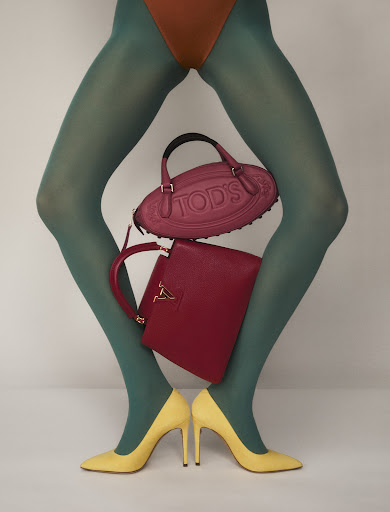 Fashion shot of a model's legs wearing green hosiery and yellow heels with a Tod's purse and a red Louis Vuitton handbag.