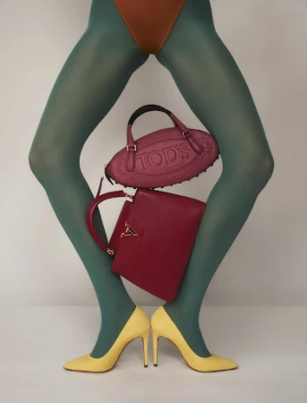 Fashion shot of a model's legs wearing green hosiery and yellow heels with a Tod's purse and a red Louis Vuitton handbag.