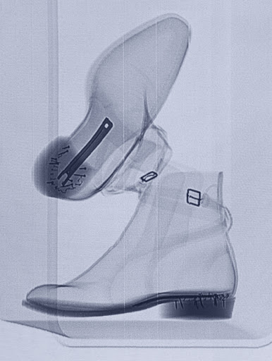 X-ray image of two boots stacked vertically, revealing internal structures and fastenings with a focus on material density and design.