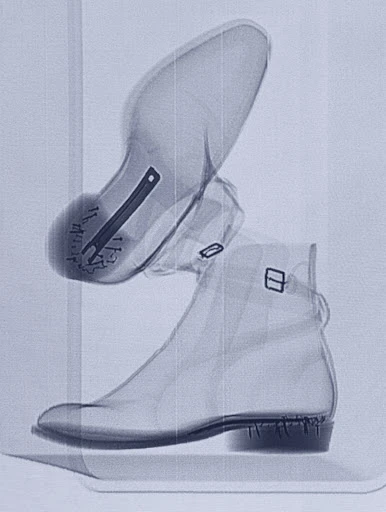 X-ray image of two boots stacked vertically, revealing internal structures and fastenings with a focus on material density and design.