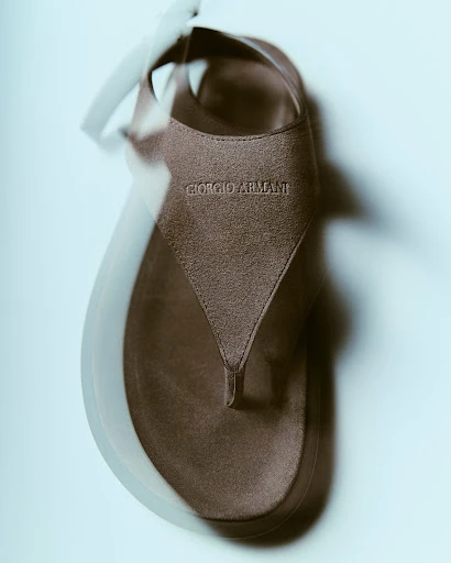 Giorgio Armani sandal displayed on a light background with blurred motion effect, showcasing its design and brand detail.
