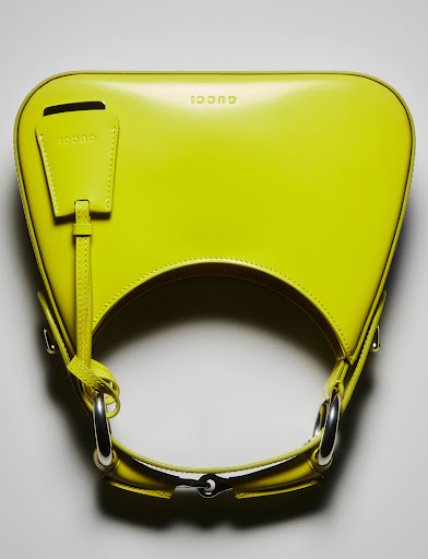 Close-up of a vibrant yellow Gucci handbag featuring silver hardware. The purse is displayed against a neutral backdrop.