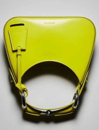 Close-up of a vibrant yellow Gucci handbag featuring silver hardware. The purse is displayed against a neutral backdrop.