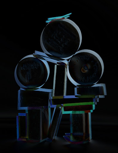 Abstract sculpture featuring stacked geometric shapes and circular discs in cool, subdued lighting against a dark background. Artful composition.
