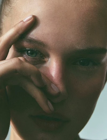 Close-up portrait of a woman with a hand raised near her face photographed by Marco Gazza
