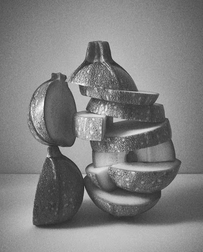 Monochromatic still life pencil drawing of stacked and sliced zucchini with textured surface and soft, diffused lighting.