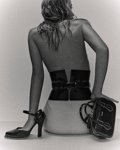 Model seated facing away wearing a wide black corset belt and handbag, photographed by Marco Gazza.