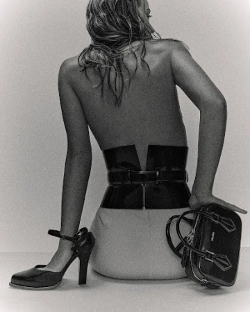 Model seated facing away wearing a wide black corset belt and handbag, photographed by Marco Gazza.