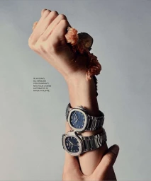 Close-up portrait by Marco Gazza of two steel wristwatches worn stacked on a raised arm against a grey seamless background