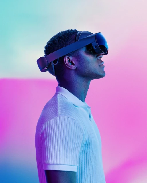Man wearing a VR headset with a white polo shirt, side profile view, lit with blue and pink light, against a blurred background.