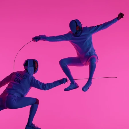 Two fencers in protective gear compete mid-air with foils against a vibrant pink background in an action shot, showcasing athleticism and skill.