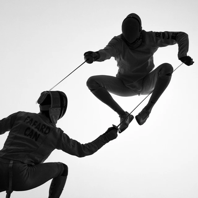 Two fencers in protective gear engaged in a fencing match, one jumping in the air with foil extended, monochrome image on a white background.