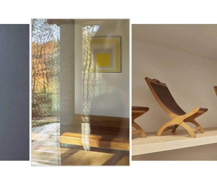 Interior scene with mid-century modern wood chairs and side table arranged on a platform against white walls, filtered light, and autumn colors.
