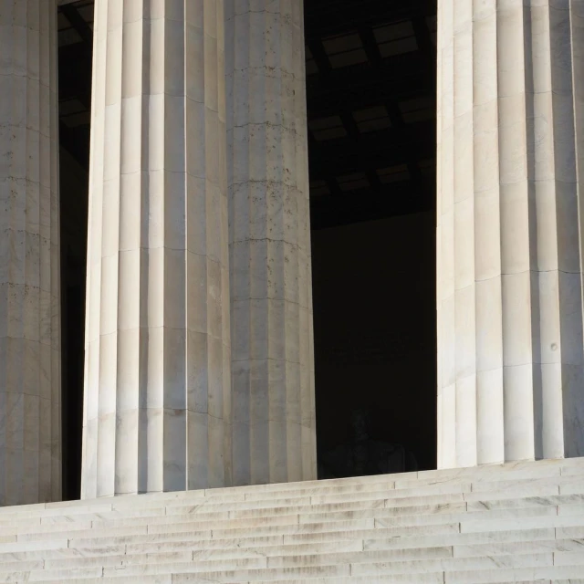 Architectural view of the Lincoln Memorial columns with stone stairs in the foreground, creating a symmetrical composition.